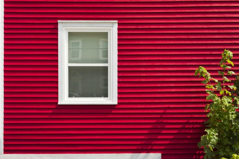 A person uses a pressure washer to clean the exterior siding of a residential house.
