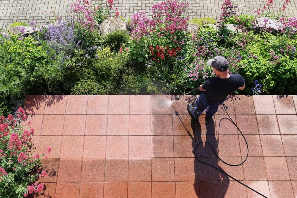 A technician cleans mildew from a concrete walkway beside a coastal Florida home.