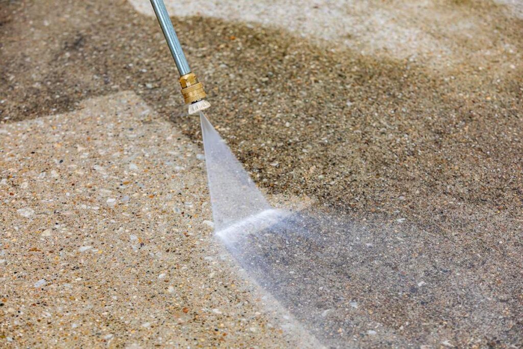 A homeowner examines evenly cleaned concrete beside a professional using controlled pressure equipment.